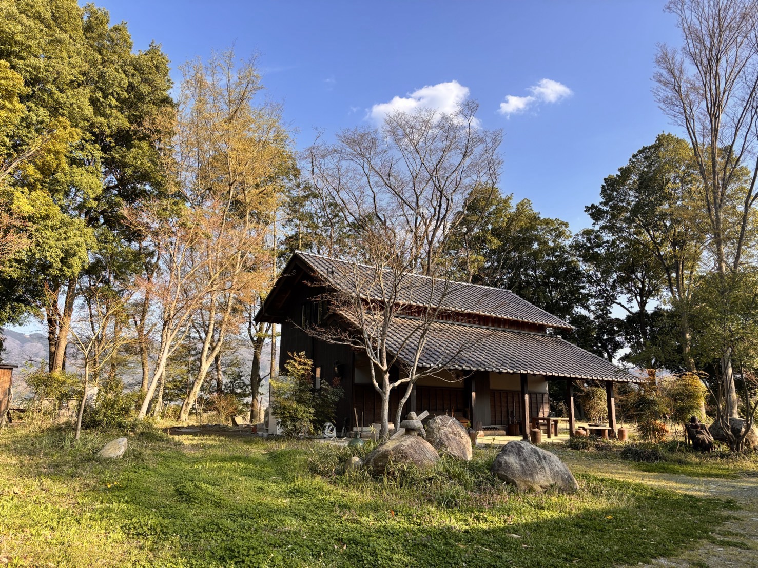 木々と石の庭に囲まれた、朔の木造の家